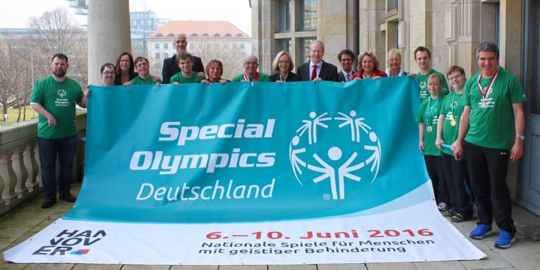 Athletinnen und Athleten sowie Repräsentanten und Organisatoren der Special Olympics präsentieren ein großes Banner