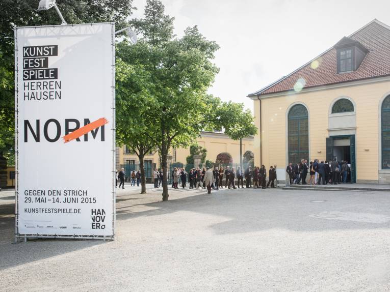 Menschen stehen in einer Schlange, um die Orangerie Herrenhausen zu betreten