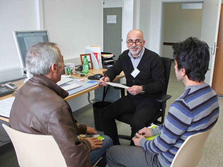 Ein Sozialarbeiter im Gespräch mit zwei Flüchtlingen