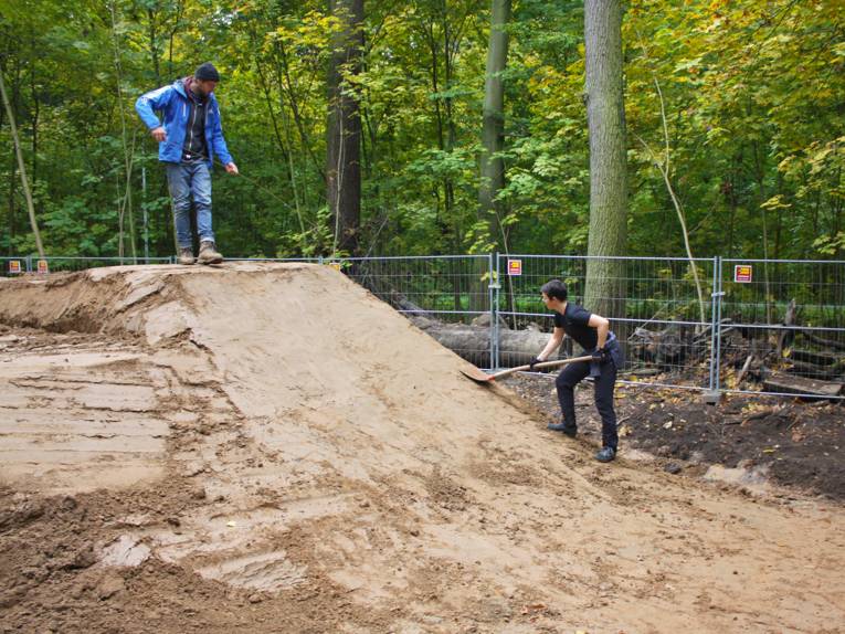 Zwei junge Leute modellieren einen Teil der Mountainbike-"Dirtline" in der Eilenriede