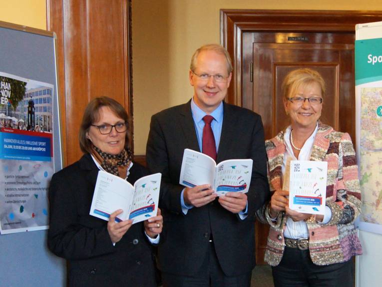Sozial- und Sportdezernentin Konstanze Beckedorf, Oberbürgermeister Stefan Schostok sowie Heike Rudolph, Leiterin des Fachbereichs Sport und Bäder, präsentieren die Broschüre
