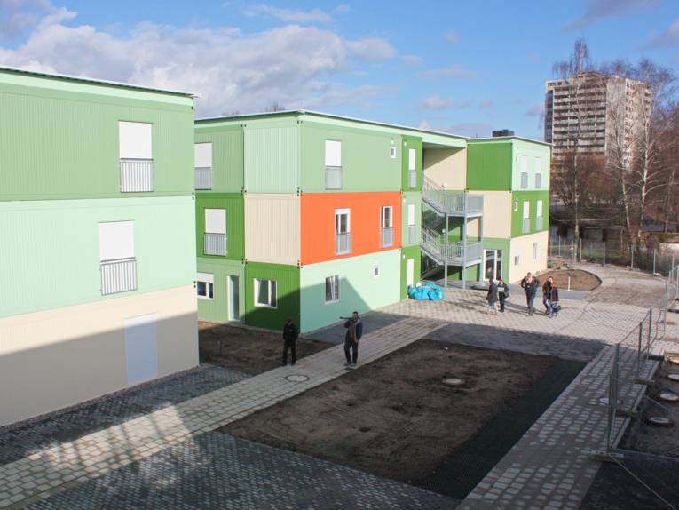 Die Flüchtlingsunterkunft besteht aus zwei- und dreigeschossigen Wohngebäuden und zum Teil eingeschossigen Gemeinschafts- und Verwaltungsgebäuden