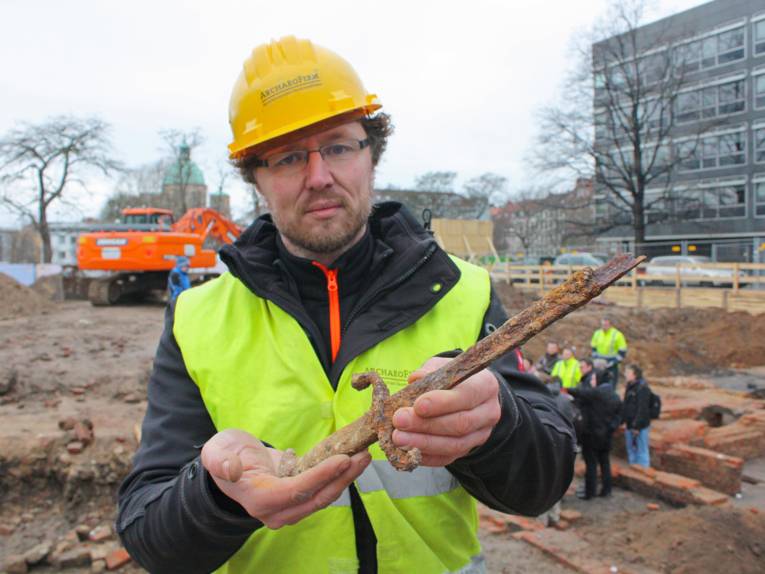 Grabungsleiter Brückner präsentiert eines der bislang gefundenen Objekte: Ein Teil eines Bajonetts, das vermutlich aus der Zeit vor dem Ersten Weltkrieg stammt