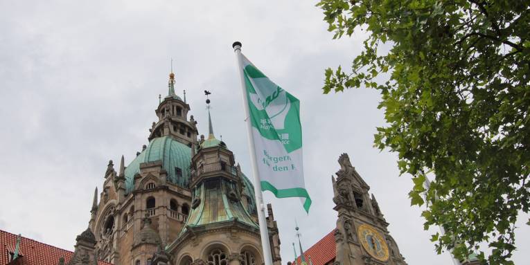 Eine Mayors for Peace-Flagge vor dem Neuen Rathaus