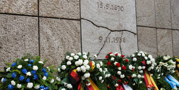 Kränze vor einem Mahnmal. 