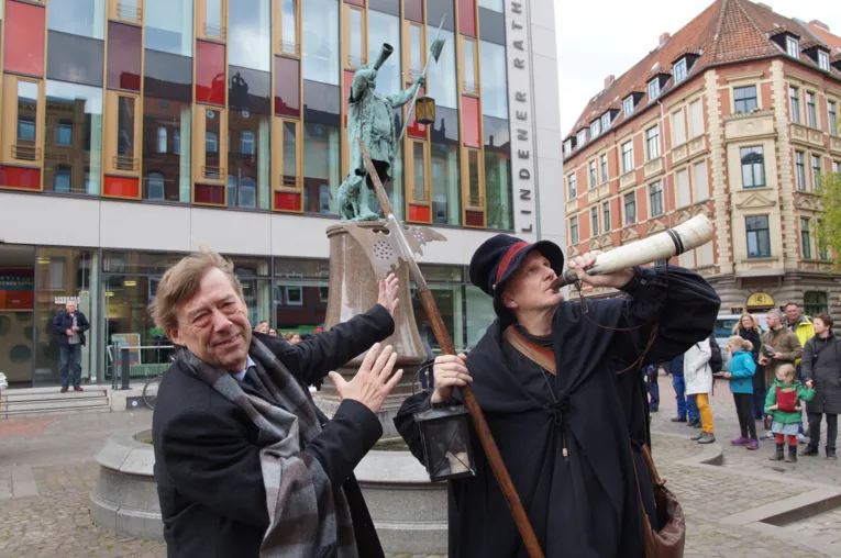 Zwei Männer vor einem Brunnen.