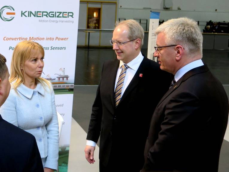 Zwei Männer und eine Frau an einem Messestand. 