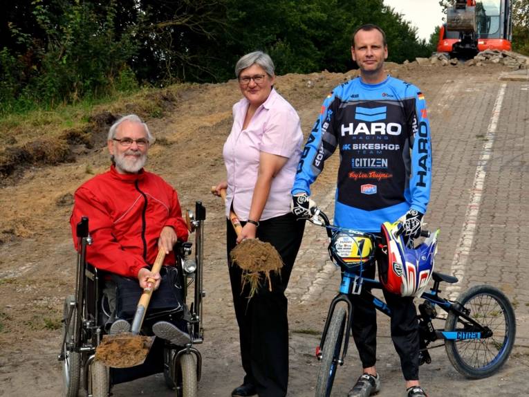 Zwei Männer und eine Frau auf einem Hügel. 