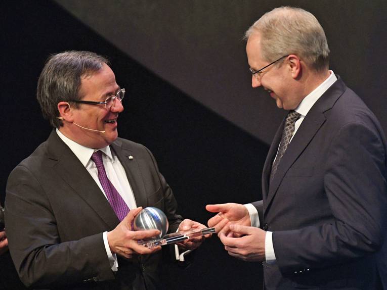 Der Ministerpräsident von Nordrhein-Westfalen, Armin Laschet, überreicht dem Oberbürgermeister von Hannover, Stefan Schostok, einen Preis in Form einer Kugel.