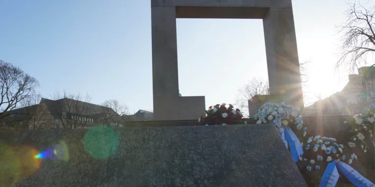 Ein Mahnmal mit Blumenkränzen davor. 