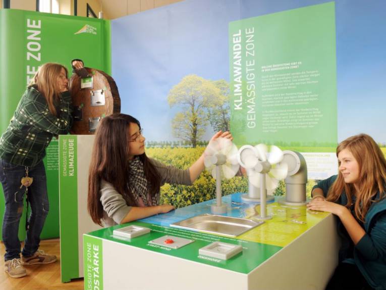 Drei Mädchen, die sich Teile einer Ausstellung angucken. 