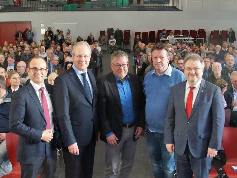 Fünf Männer in einer Aula. 