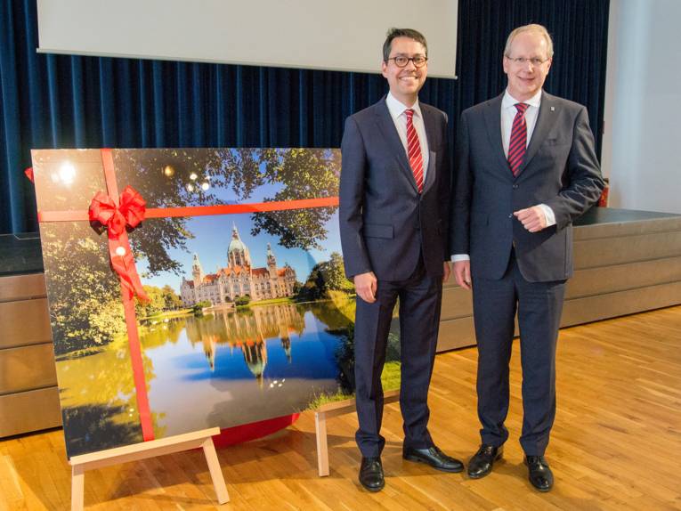 Prof. Dr. Marc Hansmann und Oberbürgermeister Stefan Schstok neben einem großen Acryl-Druck des Neuen Rathauses