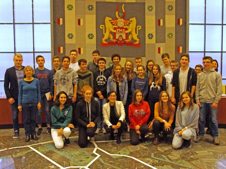 Schülerinnen und Schüler und Erwachsene in einem Saal. 