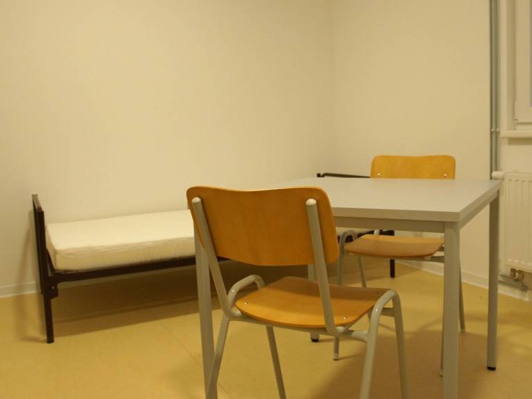 Kleines Zimmer mit einem Bett und zwei Stühlen. 