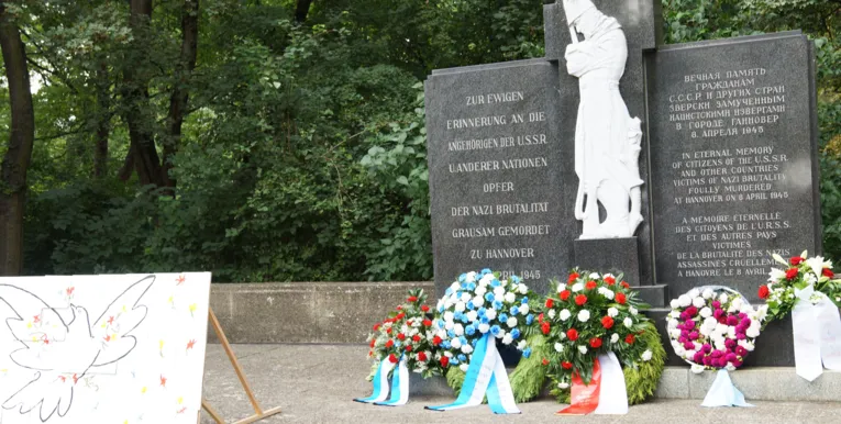 Blumenkränze vor dem Denkmal am Ehrenfriedhof. 