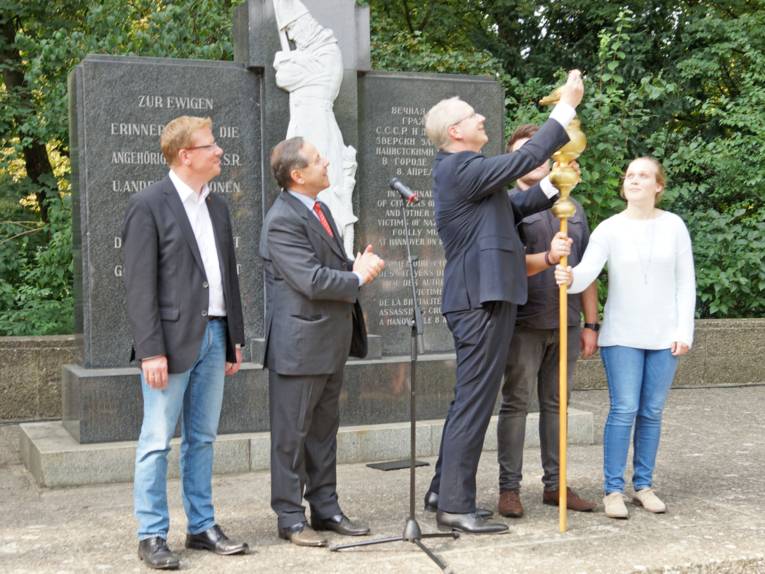 Oberbürgermeister Stefan Schostok befestigt den symbolischen Ölzweig als Zeichen für Frieden an der goldenen Taube. 