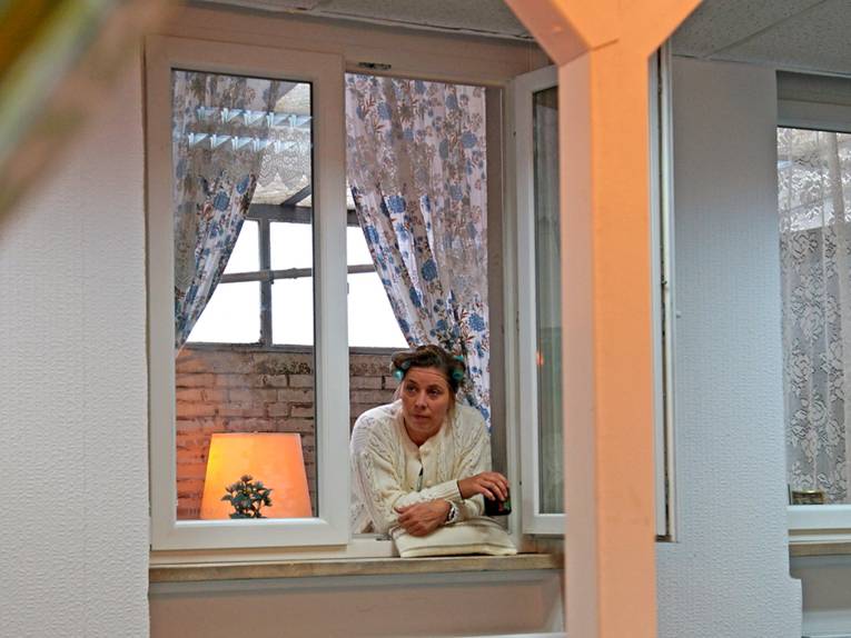 Eine Frau mit Kissen an einem Fenster