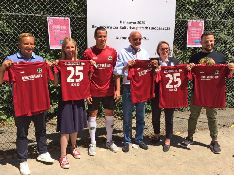 Zwei Frauen und vier Männer mit Trikots. 