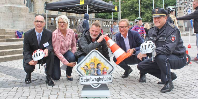 Vier Männer und eine Frau auf einem Platz.