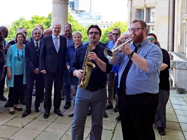 Musiker auf einem Balkon. Dahinter Zuschauerinnen und Zuschauer. 