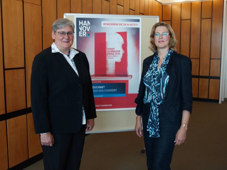 Zwei Frauen vor einem Plakat.