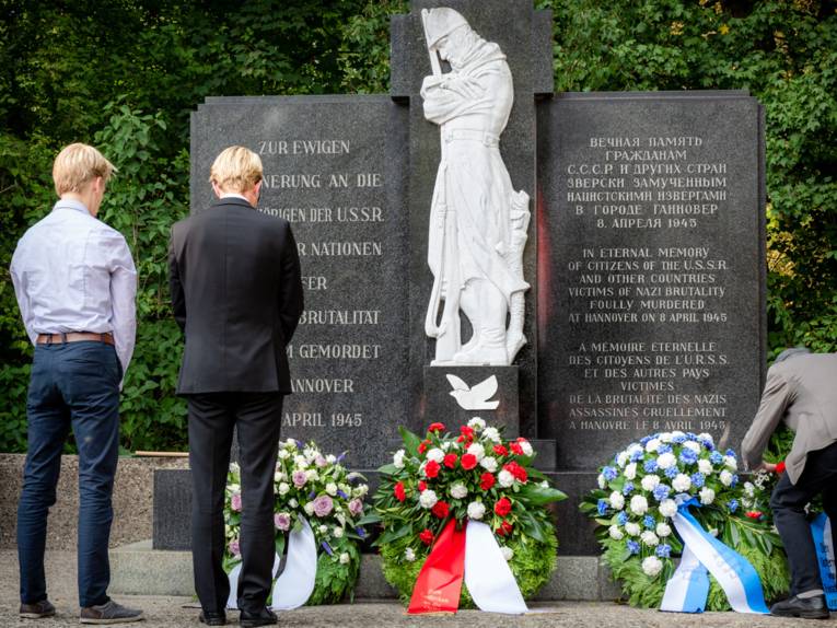 Zwei junge Menschen stehen vor dem Mahnmal auf dem Ehrenfriedhof am Maschsee-Nordufer und halten inne
