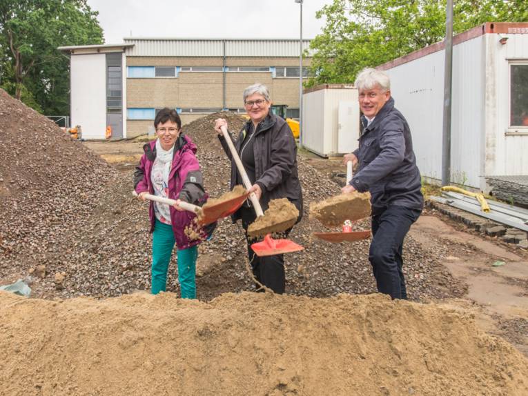 Drei Personen bei einem symbolischen Spatenstich
