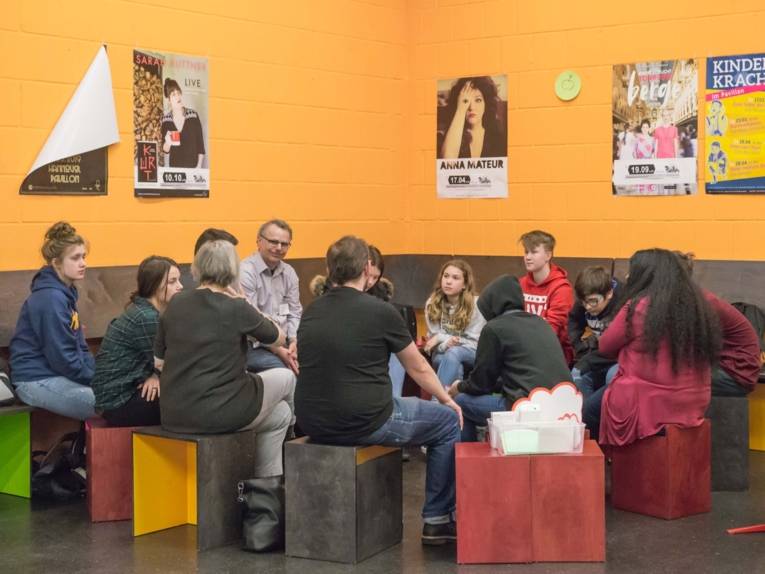 Erwachsene und Jugendliche in einer Gesprächsrunde. 