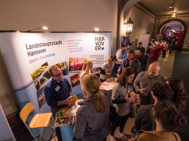 Menschen vor einem Stand in einer Halle. 