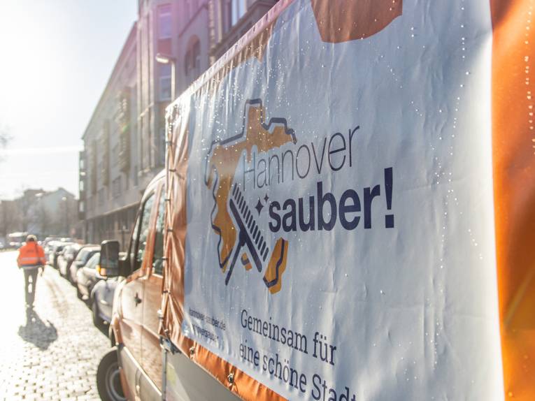 Ein Straßenreinigungsfahrzeug seitlich fotografiert im Gegenlicht