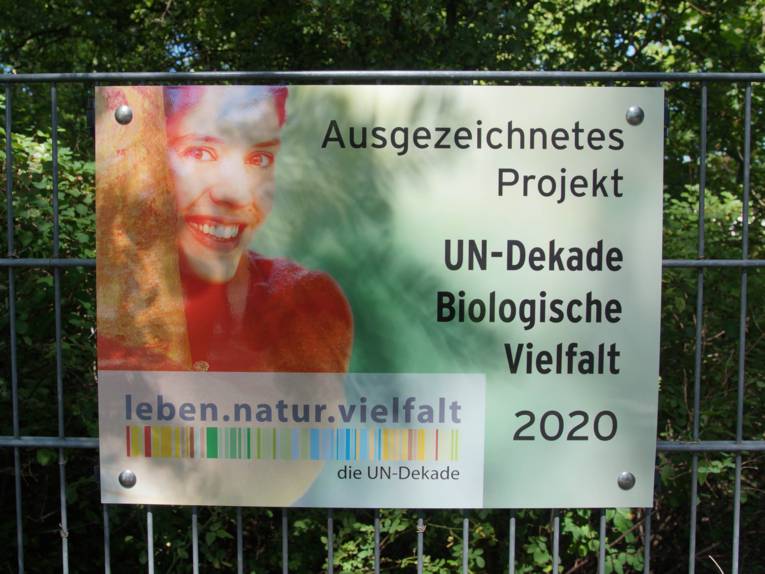 Ein Schild, auf dem steht "Ausgezeichnetes Projekt UN-Dekade Biologische Vielfalt"