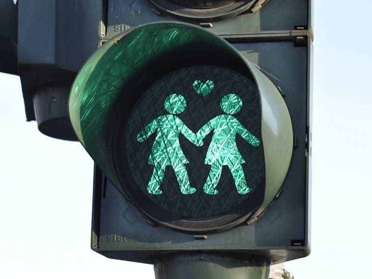 Ampel mit einem grünen Ampelzeichen, das zwei Frauen zeigt, die sich an den Händen halten. 