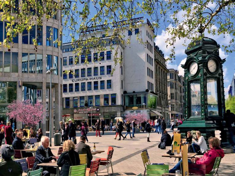 Platz in Hannovers Innenstadt. Er ist gut besucht. Menschen sitzen in einem Café. Es herrscht wuseliges Treiben. 
