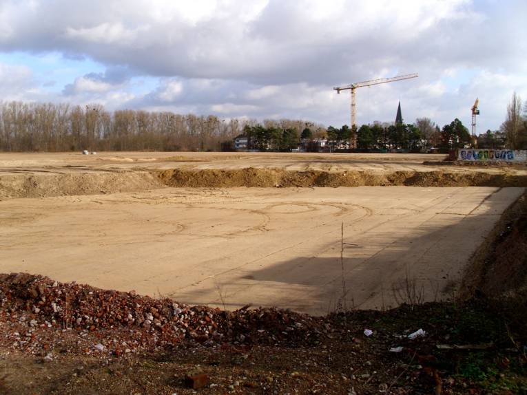 Gewalzter Sandboden auf der Baustelle, im Bildhintergrund ein großer Kran