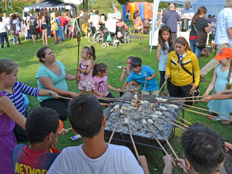 Eine Gruppe von Kindern backt im Freien am Feuer Stockbrot