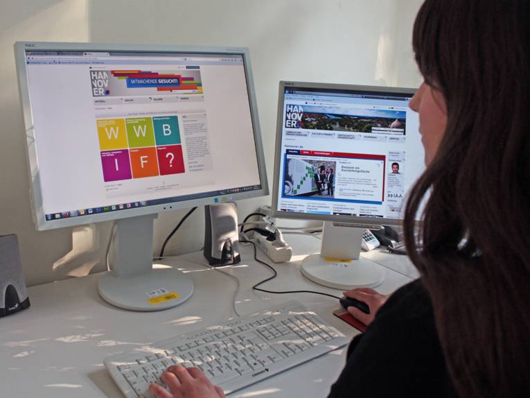 Eine junge Frau sitzt vor einem PC und erkundet den Onlinedialog.