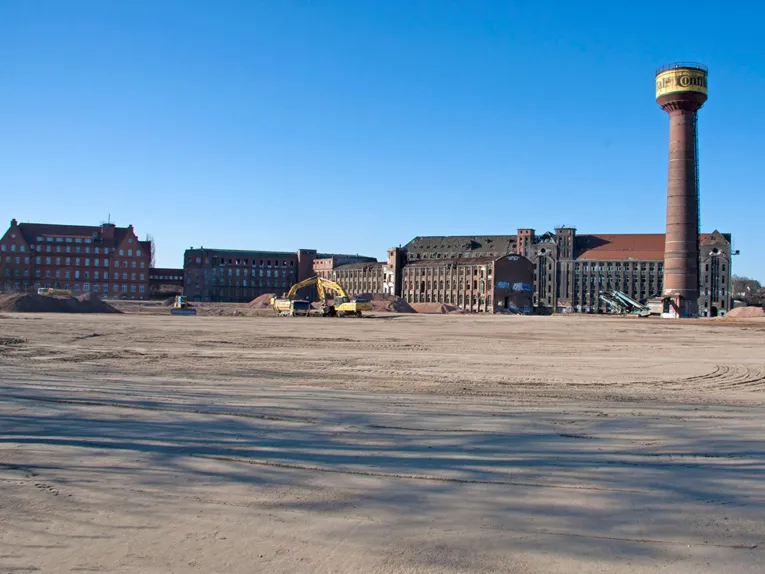 Mehrgeschossige Backsteingebäude, ein Turm mit dem Conti-Logo und Baustellenfahrzeuge