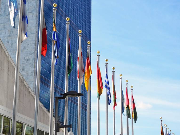 Flaggen verschiedener Nationen vor einem hohen Gebäude