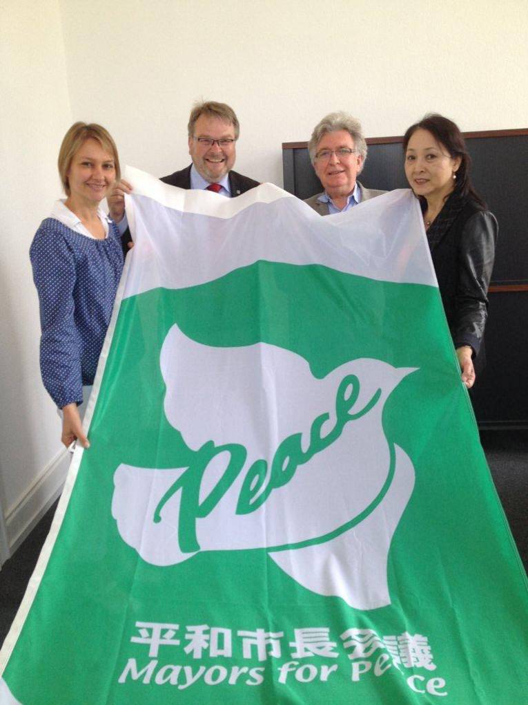 Evelyn Kamissek, Thomas Hermann, Michel Cibot und Miho Cibot mit der Flagge von Mayors for Peace 