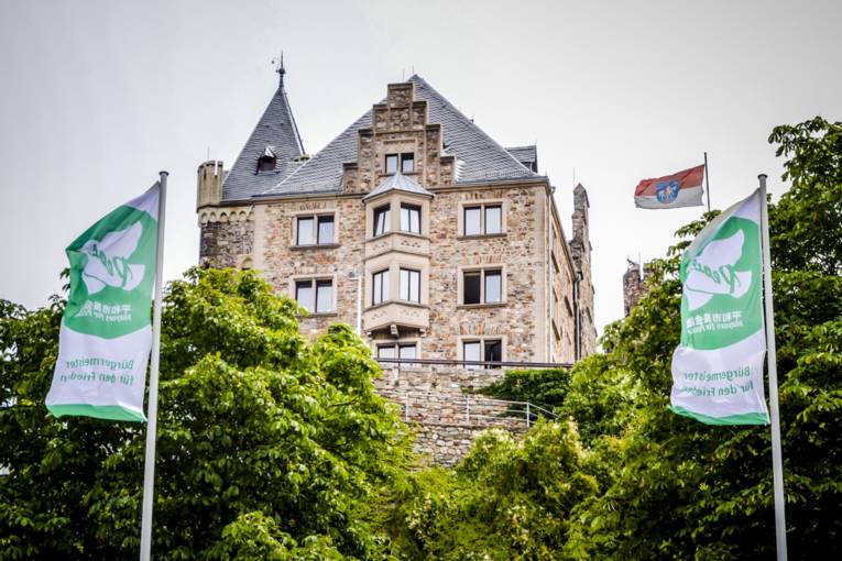 Vor der Burg Klopp weht neben der Stadtfahne von Bingen die Flagge von Mayors for Peace