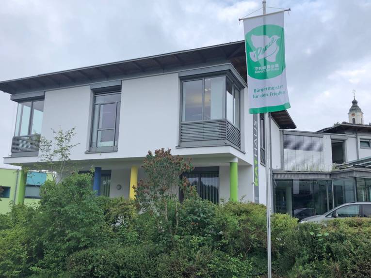 Die grün-weiße Mayors for Peace-Flagge weht am Flaggenmast vor dem Rathaus der Gemeinde Bodnegg.