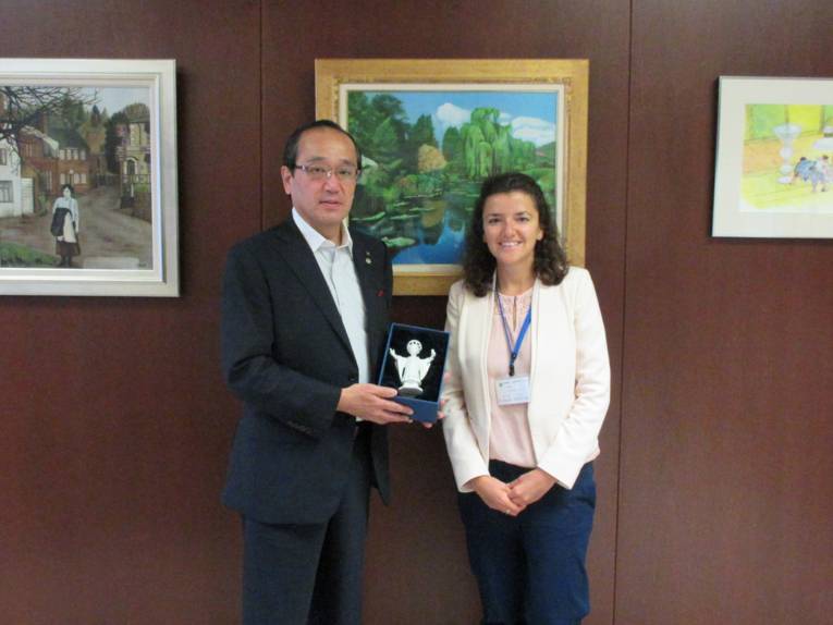 Der Bürgermeister von Hiroshima, Kazumi Matsui, und Ricarda Schuller bei der Übergabe des Gastgeschenkes, dem Münchner Kindl als Porzellanfigur.