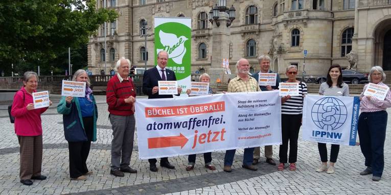 Oberbürgermeister Stefan Schostok mit einer Gruppe von Personen vor dem Rathaus, die Transparente mit der Aufschrift "atomwaffenfrei jetzt" halten.