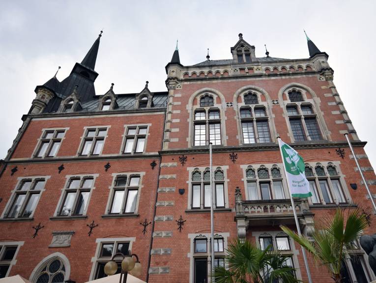 Ein historisches Backsteingebäude, davor eine gehisste Mayors-for-Peace-Flagge