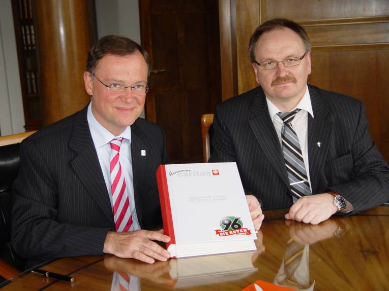 Oberbürgermeister Weil präsentiert das Kampagnen-Buch, mit dem die Caritas Hannover gemeinsam mit Hannover 96 für eine kinderfreundliche Stadt und Region Hannover werben