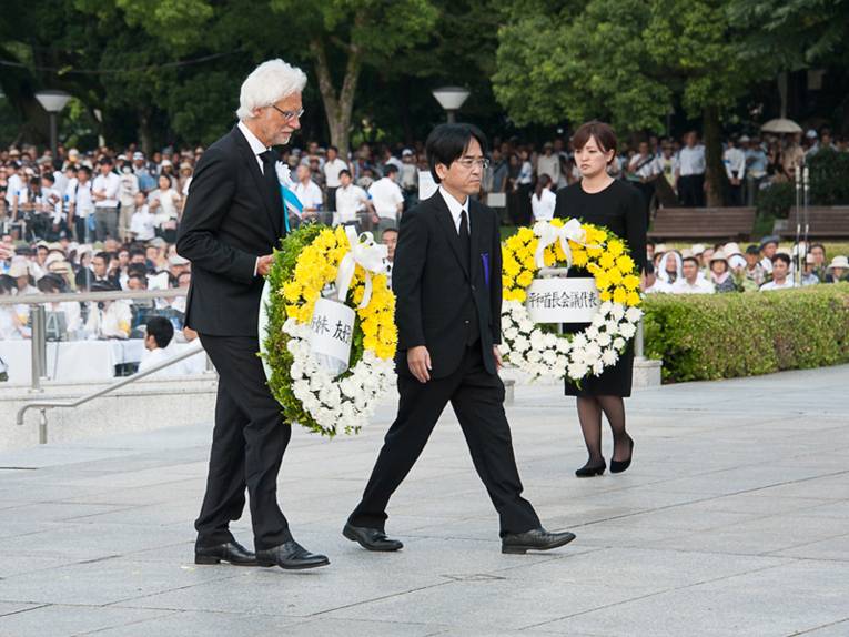 Bürgermeister Strauch trägt einen Gedenkkranz, begleitet vom japanischen Repräsentanten in Hiroshima, Herrn Tsumura.