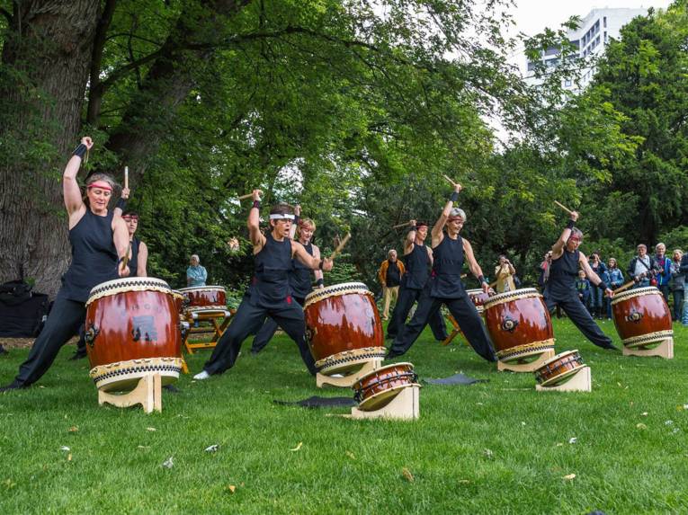 Frauen in einem Park, die Trommeln schlagen. 
