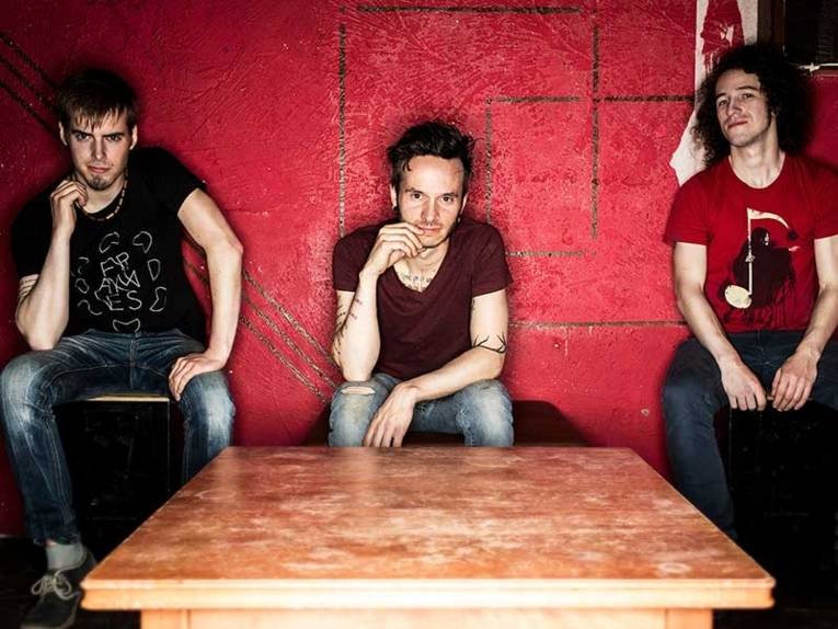 Drei Musiker vor einer rot gestrichenen Wand