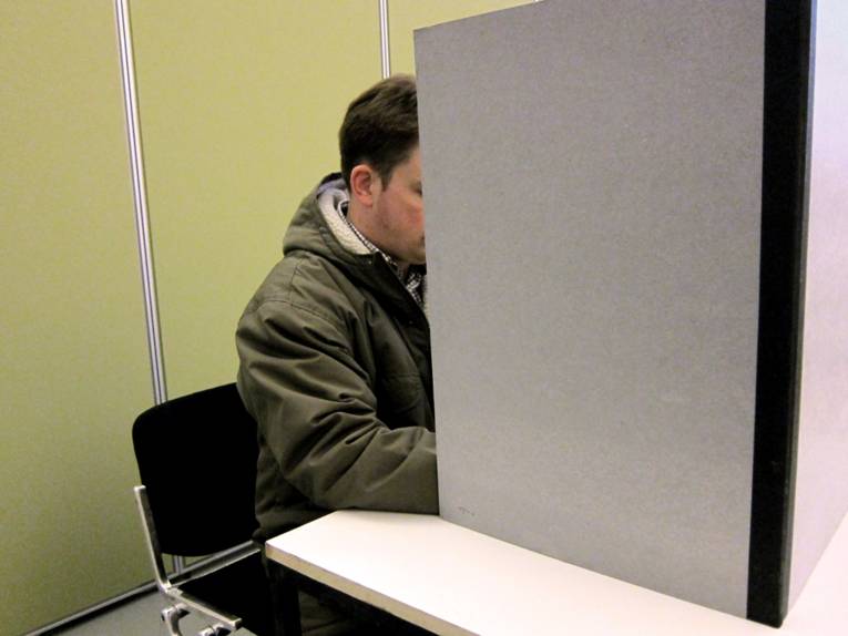 Nachgestellte Szene: Ein Wähler füllt seinen Stimmzettel in der Wahlkabine aus